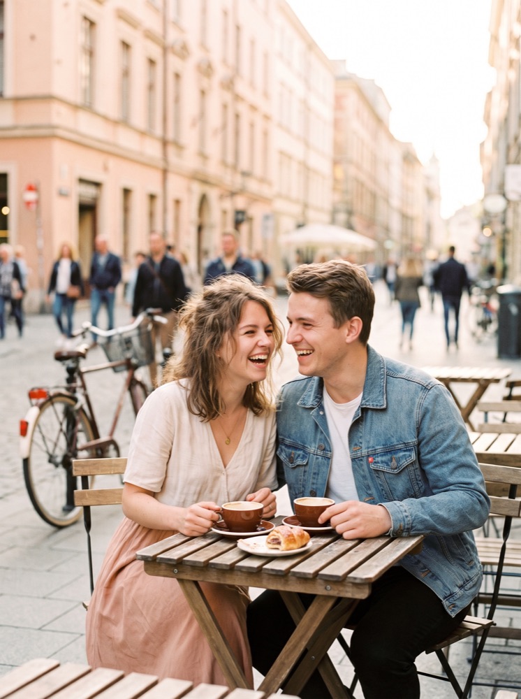 Two people laughing together over coffee at an outdoor cafe